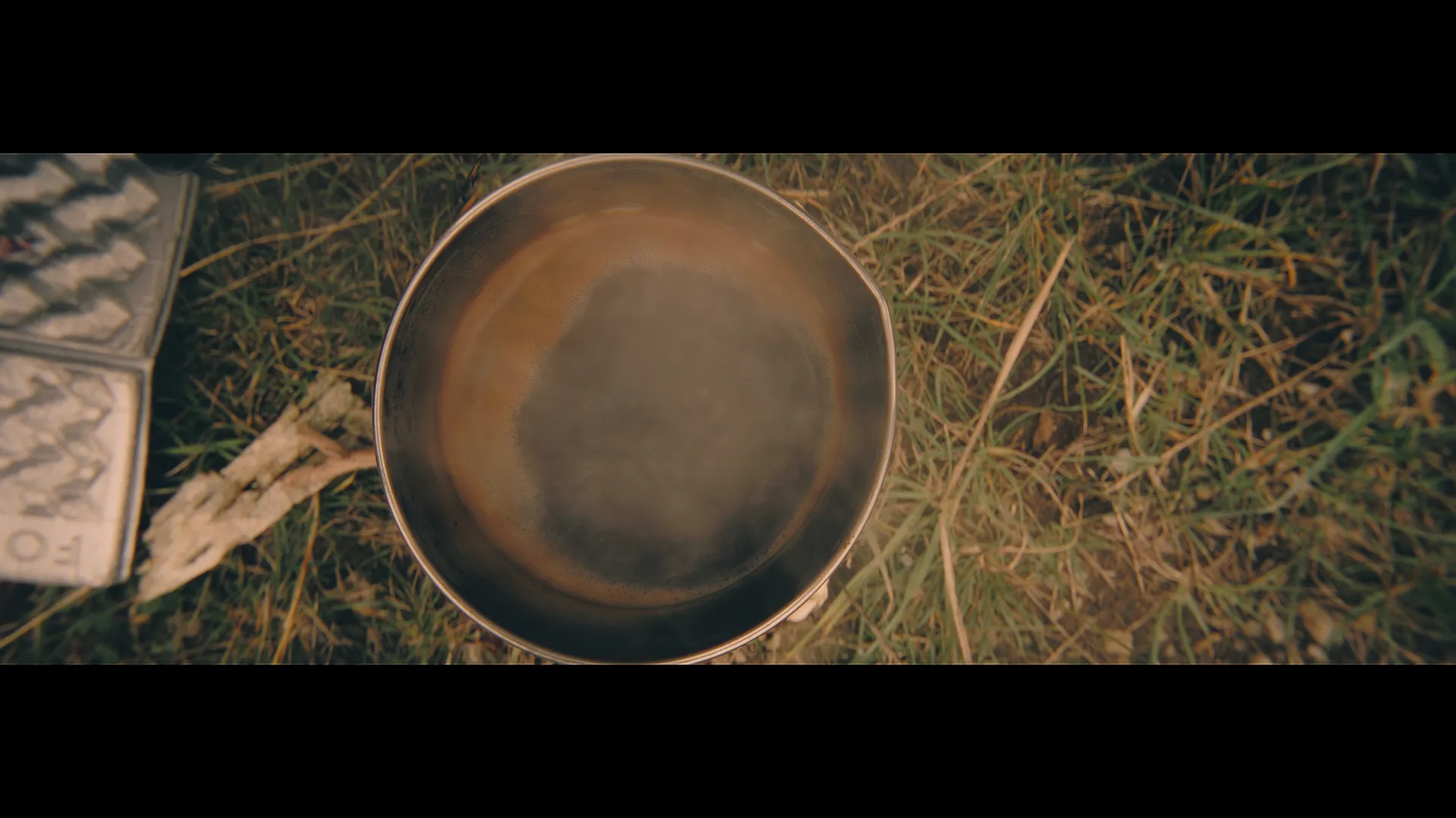 Dampfender Kaffee in einer Metalltasse auf dem Waldboden